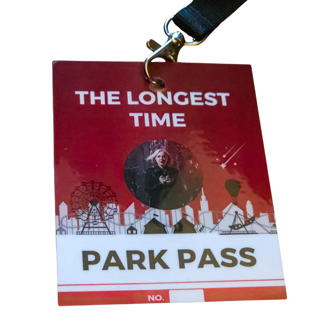 A novelty park pass badge with a red and white design, featuring the text 'THE LONGEST TIME PARK PASS' and a circular photo cutout, attached to a black lanyard with a silver clasp.